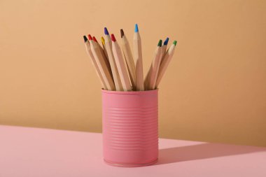 Bej arka planda pembe teneke kalemler.