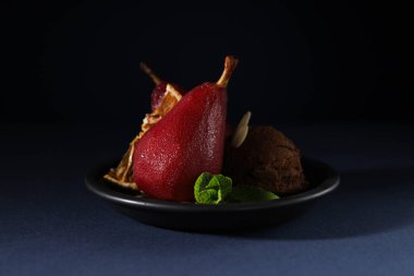 Koyu mavi arka planda, şarabın içindeki armutlar tabakta, kapat