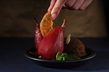 Armutlar tabakta, kadın eli koyu ahşap arka planda, kapat