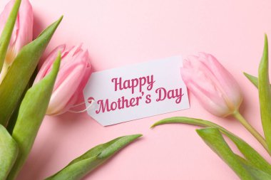 Anneler Günün kutlu olsun pembe laleler ve pembe arka planda Anneler Günü 'nü kutlayan bir kart.