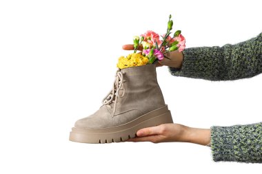 Yaratıcı bir şekilde bir saksı olarak kullanılan ayakkabı güzel çiçekler tutuyor, beyaz üzerinde izole edilmiş.