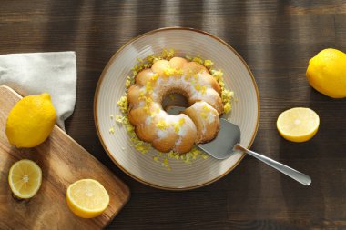 Tabakta limonlu pasta, tahta tahta tahta tahta ve ahşap arka planda limon, üst manzara.