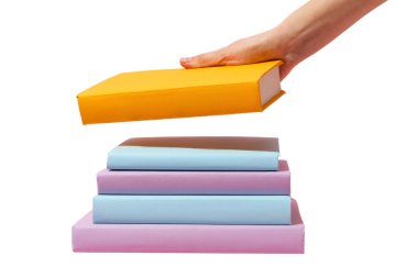 El, sarı bir kitabı renkli çalışma materyallerinin üzerine koyar, beyaza izole edilmiş.