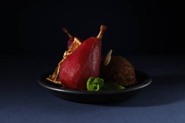 Koyu mavi arka planda, şarabın içindeki armutlar tabakta, kapat