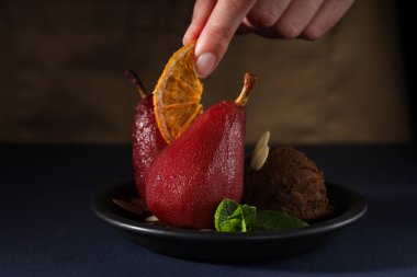 Armutlar tabakta, kadın eli koyu ahşap arka planda, kapat