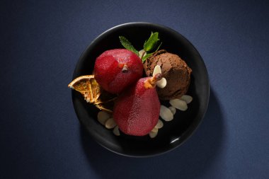 Dondurma ve armutlar tabakta, koyu mavi arka plan, üst manzara.