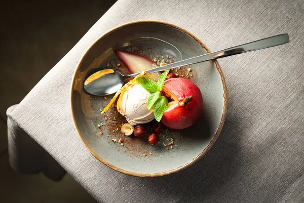 Dondurma ve armut şarapta tabakta ve kaşık arka planda, üst manzara