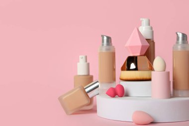 Vakıf şişeleri, kozmetik fırça ve pembe arka planda süngerler, metin için boşluk