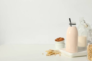 Alternatif süt şişeleri ve hafif arka planda bitkisel malzemeler, metin için boşluk