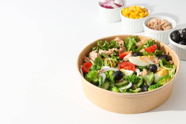 Işık masasındaki karton tabakta ton balığı salatası..