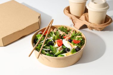 Işık masasındaki karton tabakta ton balığı salatası..