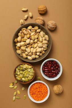 Bej arka planda fasulye, fındık ve tohumlar, üst manzara.