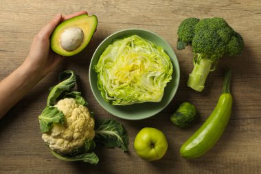 Protein sebzeleri ve kadın eli ahşap arka planda.