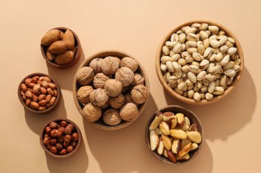 Bej arka planda ahşap kaselerde çeşitli fındıklar