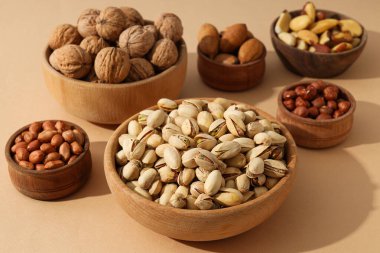 Bej arka planda ahşap kaselerde çeşitli fındıklar