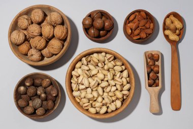 Gri arka planda ahşap kaselerde çeşitli fındıklar