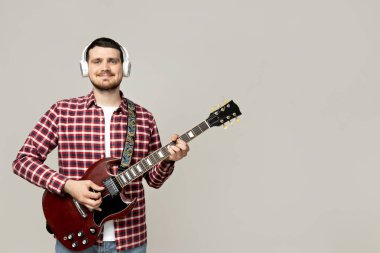 Kulaklıklı ve gitarlı çekici bir genç.