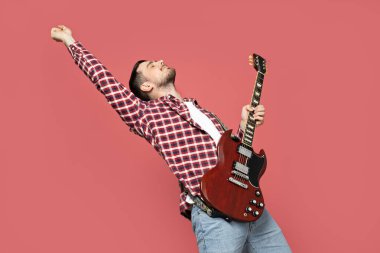 Pembe arka planda gitar çalan çekici bir genç adam.