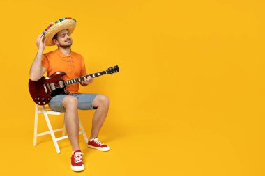 Meksika şapkasıyla gitar çalan çekici genç adam.