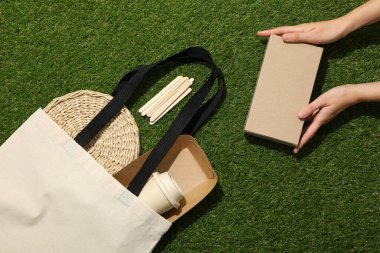 Pamuk torba ve kutu ellerinde yeşil arka plan, üst görünüm