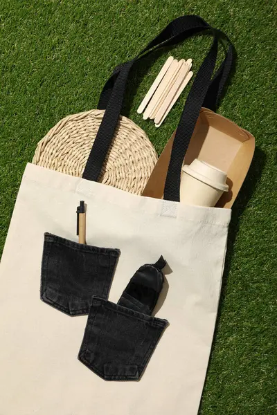 Kağıt bardaklı pamuk torba, yeşil arka planda kutu ve tepsi, üst görünüm