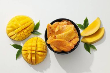 Bir kase kurutulmuş mango cipsi ve taze kesilmiş mango.
