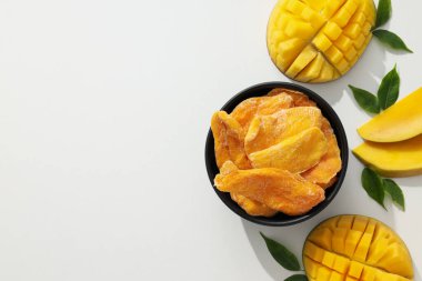 Bir kase kurutulmuş mango cipsi ve taze kesilmiş mango.