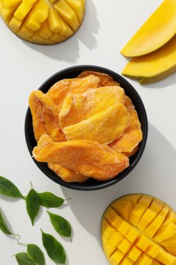Bir kase kurutulmuş mango cipsi ve taze kesilmiş mango.