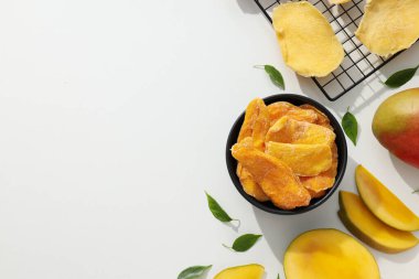 Bir kase kurutulmuş mango cipsi ve taze kesilmiş mango.