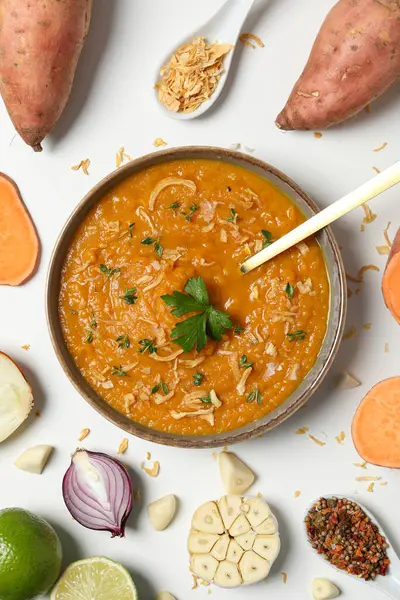 Tatlı patates püresi kasede, malzemeler ve baharatlar beyaz arka planda, üst manzara