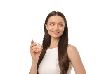 Kadın beyaz arka planda neşeyle bir parfüm şişesi tutuyor.