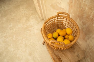 Limonlar ve limonlar ahşap bir masada örülmüş bir sepetin içinde otururlar.