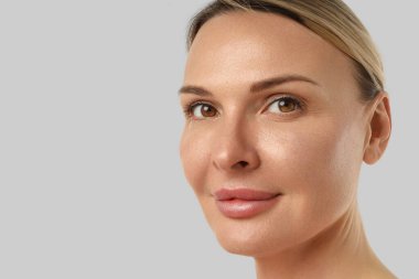 Parlak tenli bir kadın kendinden emin bir şekilde izleyiciye bakar.