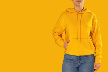 Sarı kapüşonlu ve kot pantolonlu kadın, renkli arka plan