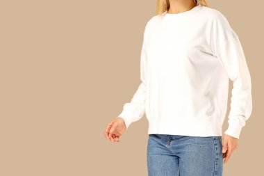 Beyaz kazak ve kot pantolon giyen bir model.