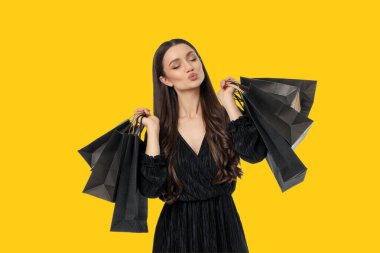 Uzun saçlı kadın, birden fazla alışveriş çantasıyla poz veriyor.