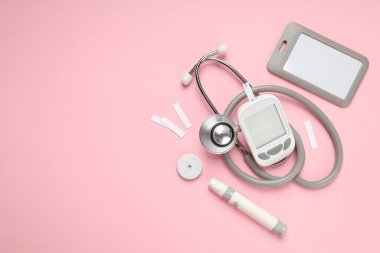 Pembe üzerinde kan şekeri monitörü ve steteskop.