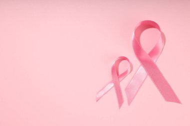 Yumuşak pembe arkaplanda iki pembe kurdele var.