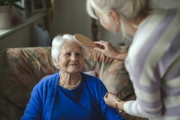Woman combing hair of elderly mother
