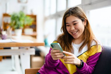 Çatı katında akıllı telefon kullanan genç kadın.