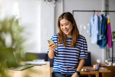 Çatı katında akıllı telefon kullanan genç kadın.