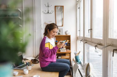 Çatı katında akıllı telefon kullanan genç kadın.
