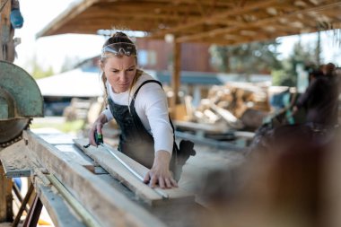 Bir kereste fabrikasında ahşap kalaslarla çalışan bir kadın.