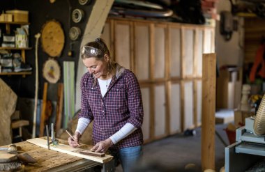 Marangozluk atölyesinde ahşap işçiliği yapan bir kadın.