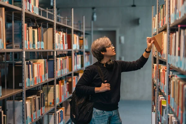 Portré Ázsiai Diák Pick Könyv Könyvespolcról Könyvtárban — Stock Fotó