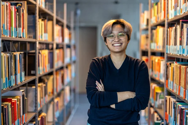 stock image Portrait of smiling asian student standing with arms crossed in college library