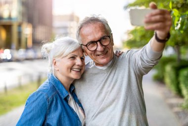 Şehirde akıllı telefon kullanan kıdemli bir çift.