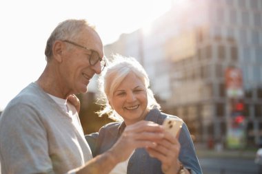 Şehirde akıllı telefon kullanan kıdemli bir çift.