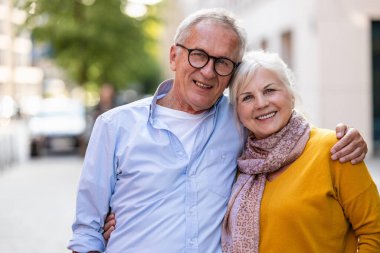 Şehirde kucaklaşan mutlu yaşlı bir çiftin portresi.