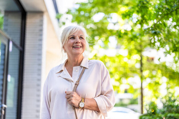 Портрет счастливой пожилой женщины, стоящей в городе